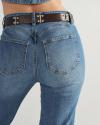 Close-up of a person wearing light blue denim jeans and a brown belt with metal studs, showing the back pockets and waist.